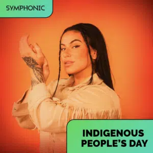 A person with long dark hair and a tattoo on their hand poses in front of an orange background. Text reads "SYMPHONIC," "INDIGENOUS PEOPLE'S DAY," and highlights a special Spotify playlist.